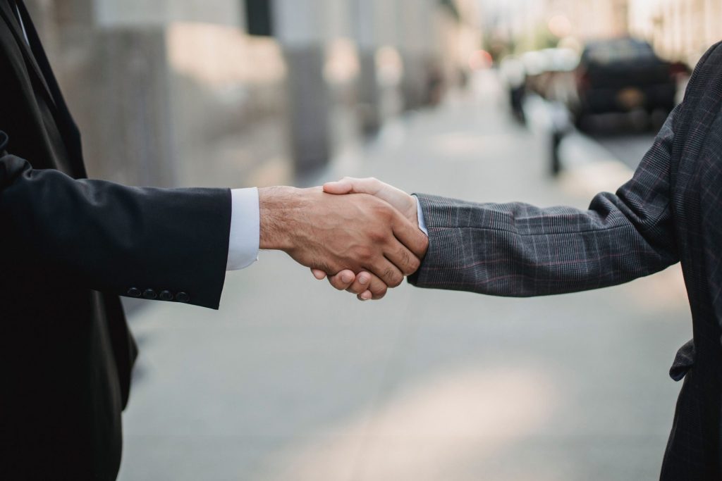 Close-up of a business handshake between professionals outdoors.
